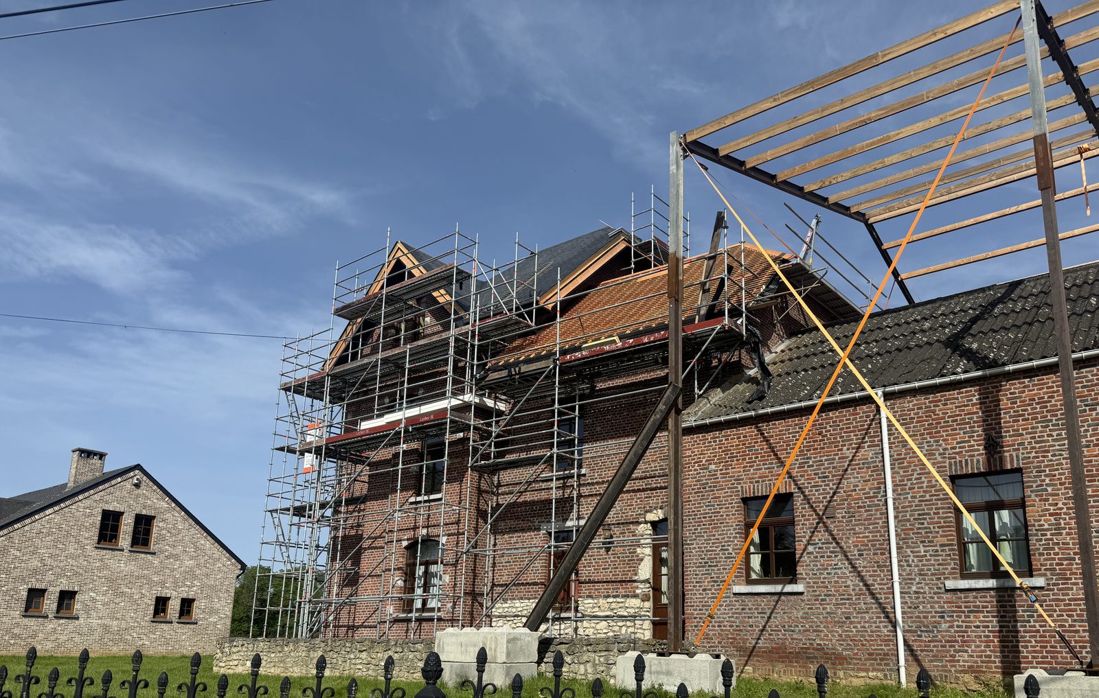 Façade angle avec échafaudage et nouvelle charpente acier visible à droite