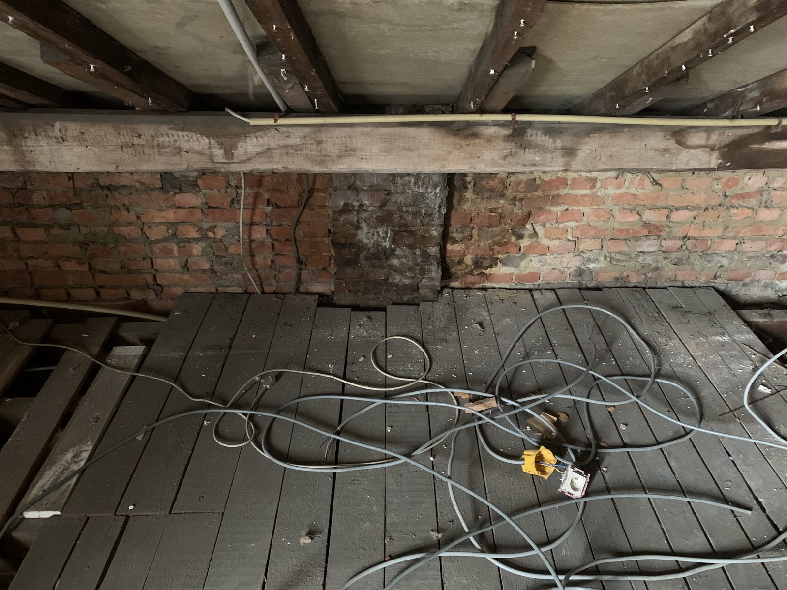 État intérieur des combles avant mission : structure bois et briques visibles, électricité éparse